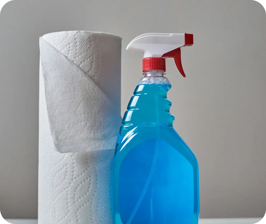 A laundry room scene with a gallon of Alpha Clean bleach placed next to a washing machine, with clean white towels and a measuring cup showing safe bleach usage.